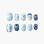 Handmade press-on nails with blue plaid and pearl bow designs arranged on white background