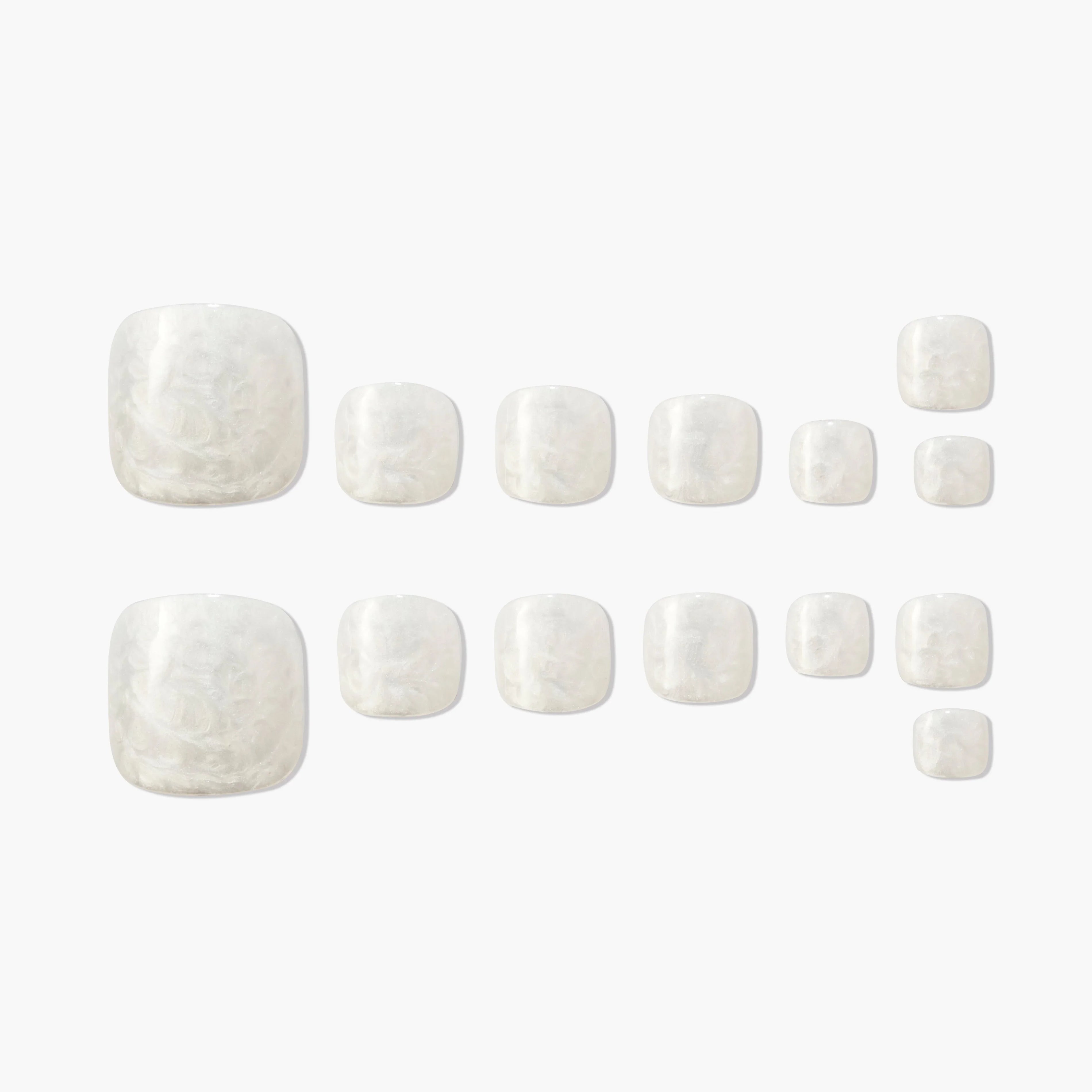 Set of glossy white marble press-on toenails arranged on a plain background