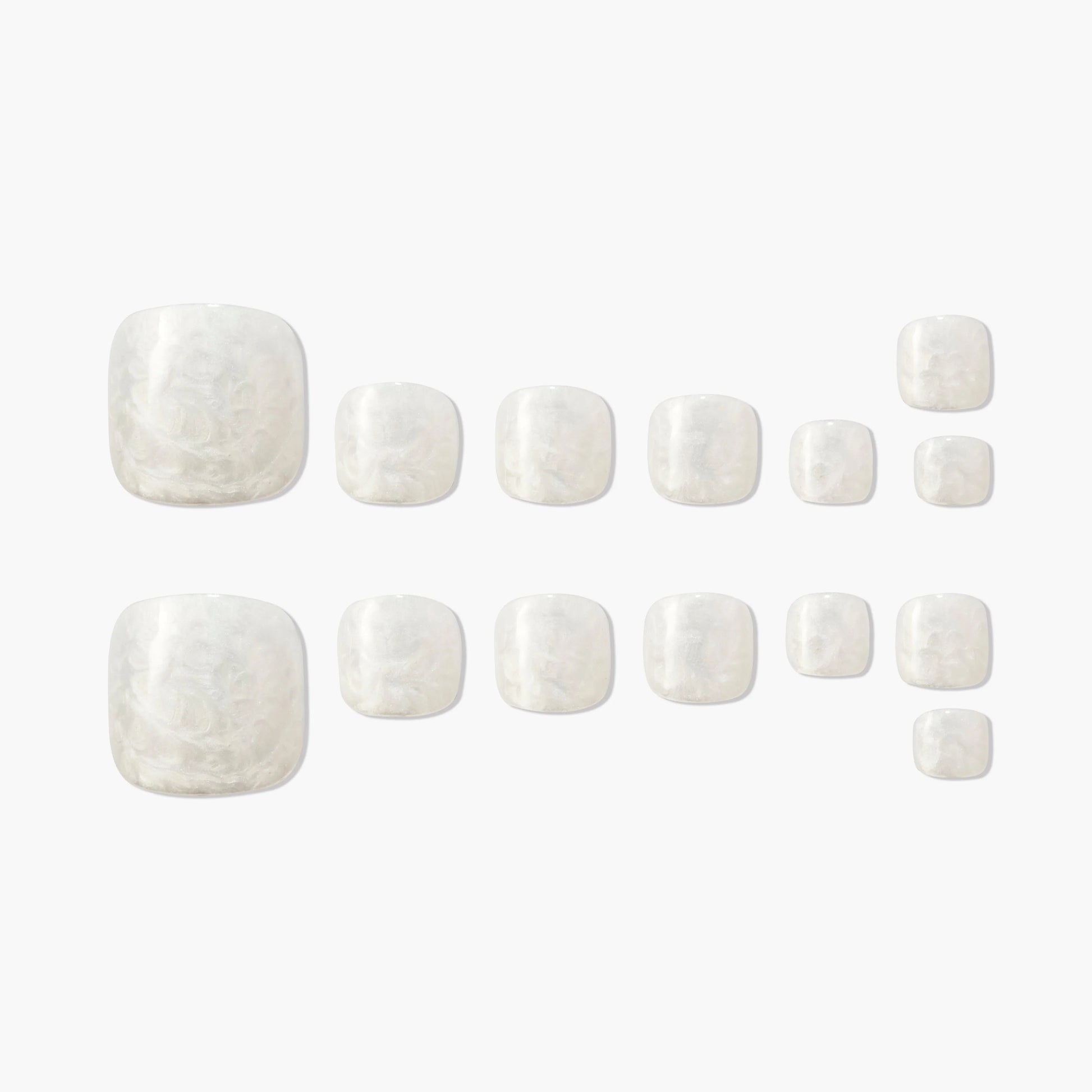 Set of glossy white marble press-on toenails arranged on a plain background