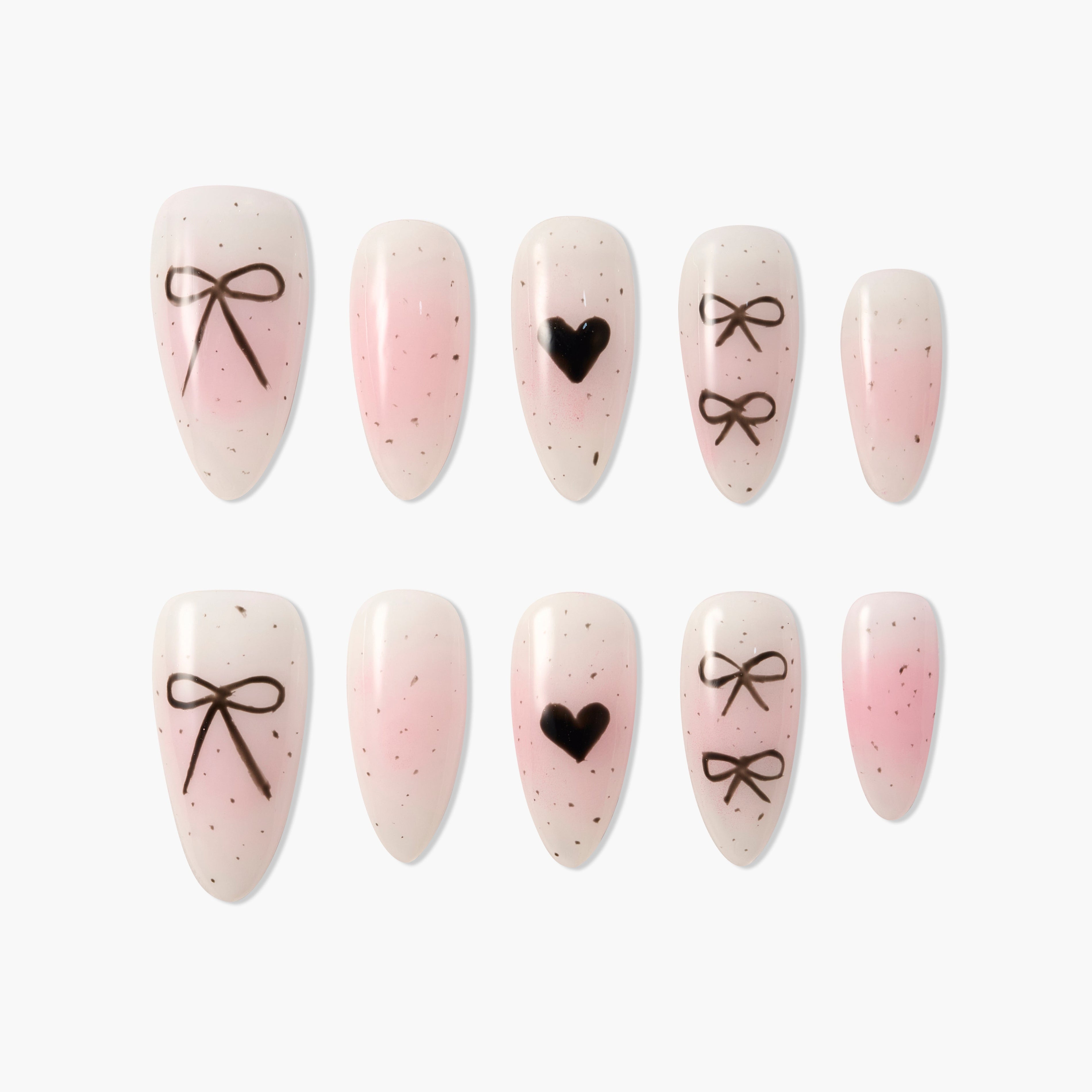 Pink and nude press-on nails with black bow and heart designs, speckled accents