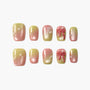 Gradient pink and yellow press-on nails with pearl accents and 3D bow designs, arranged on white background