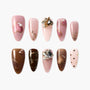 Handmade press-on nails in pink and brown shades with heart designs, pearls, and rhinestones