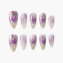 Set of handmade press-on nails with purple floral and gradient designs on a white background