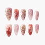 Handmade press-on nails with pink floral designs, gold accents, and pearl embellishments