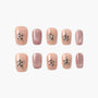 Handmade nude press-on nails with silver star and pearl accents, plus glitter pink nails.