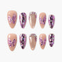 Glossy press-on nails with nude and glitter designs, purple butterfly charms, rhinestone accents