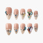 Nude and gold press-on nails with glitter, rhinestones, pearls, moon and heart gems