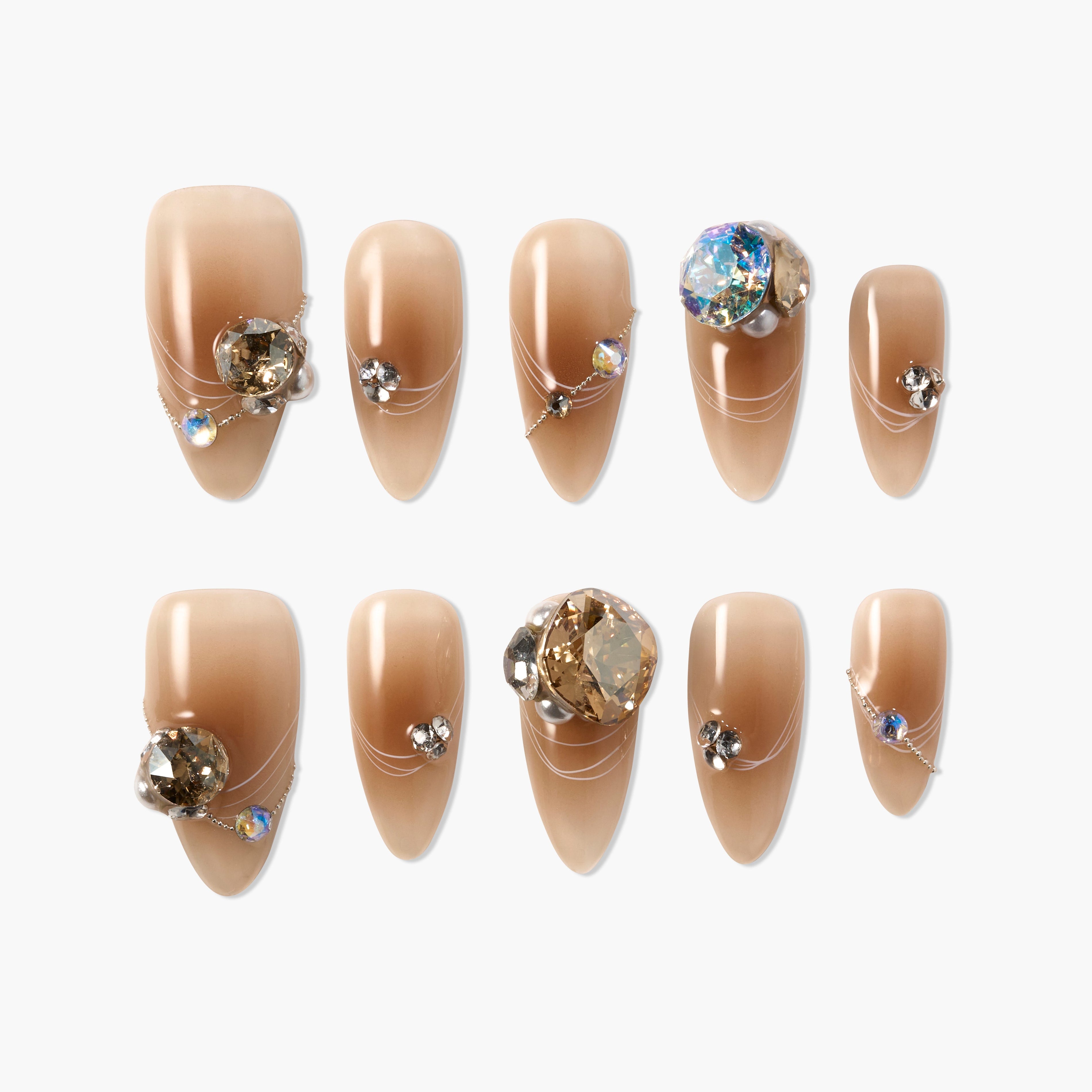 Glossy nude almond press-on nails with 3D rhinestone and chain accents, arranged on white background.