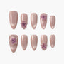 Handmade pink press-on nails with 3D purple floral accents, medium almond shape