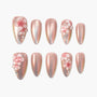Iridescent pink press-on nails with 3D floral designs and rhinestone accents, displayed on white background.