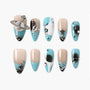 Blue and nude press-on nails with star and planet charms, rhinestones, and galaxy designs.