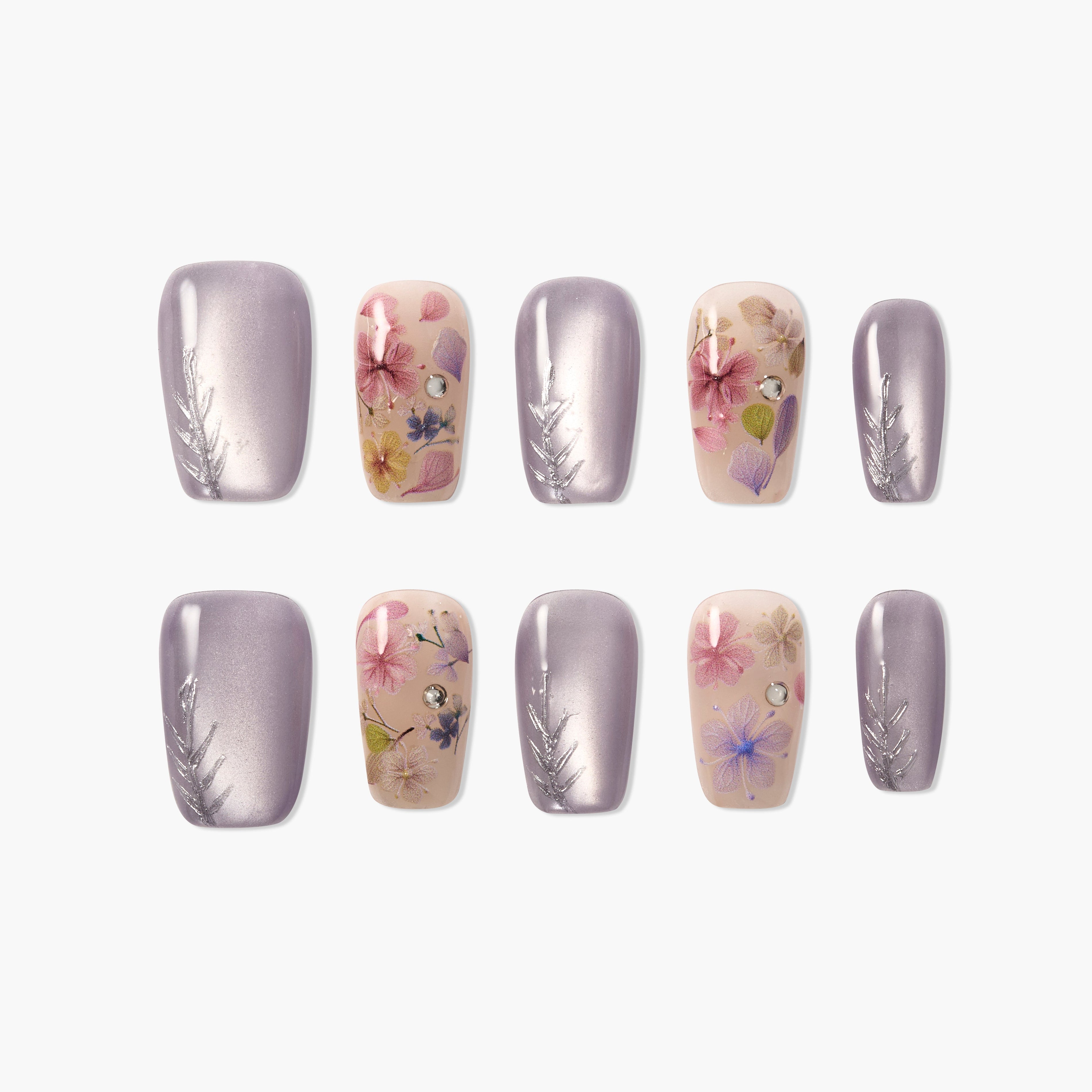 Handmade press-on nails with purple metallic polish, floral designs, and rhinestone accents
