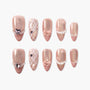 Handmade pink press-on nails with glitter, pearl accents, bows, and plaid patterns