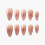 Handmade nude pink press-on nails with glitter and 3D floral accents, almond shape