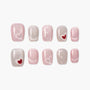 Set of pink and nude press-on nails with heart and polka dot designs on white background