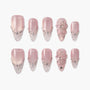 Pink and clear press-on nails with rhinestone accents and 3D floral designs on white background