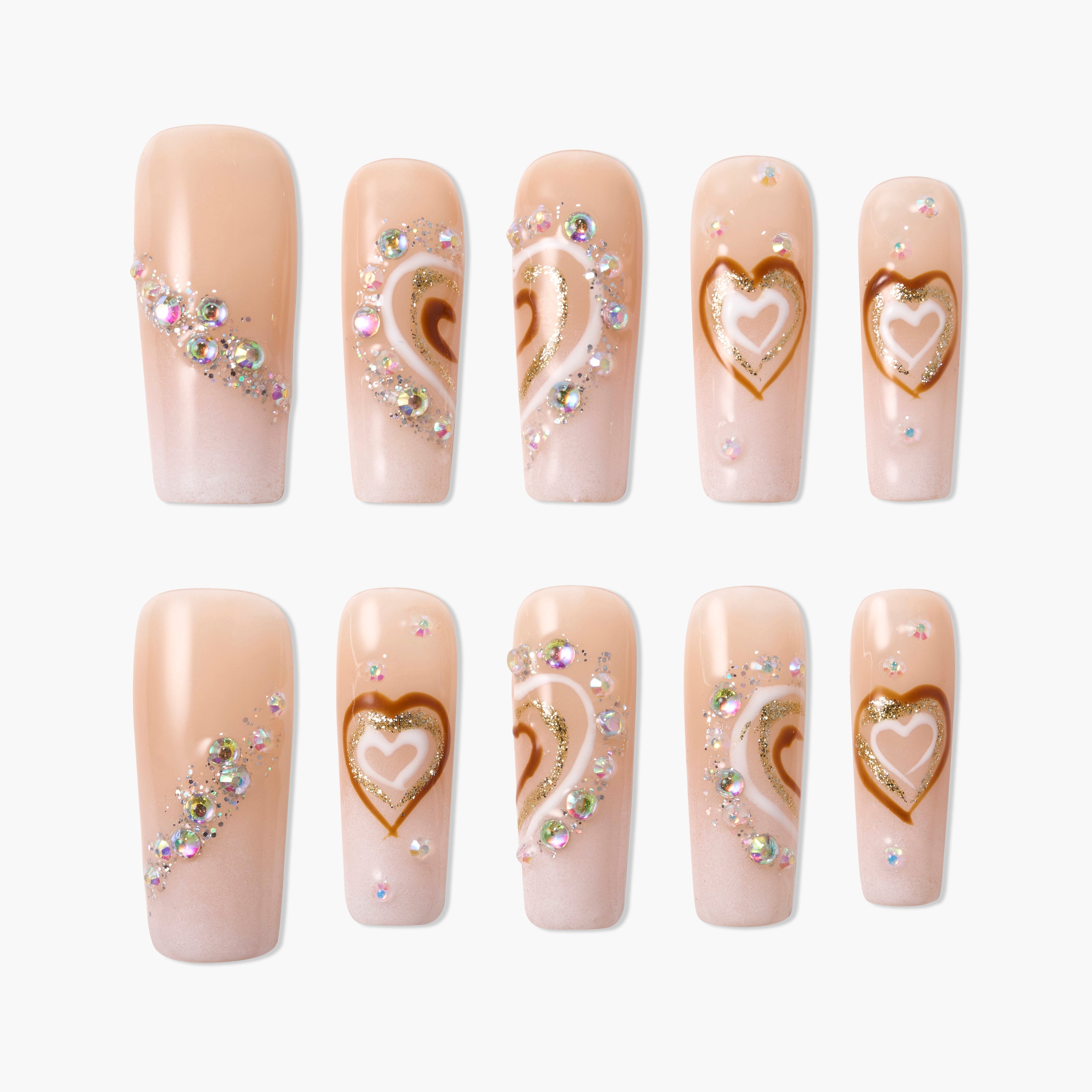 Nude pink press-on nails with gold heart designs and sparkling rhinestone accents