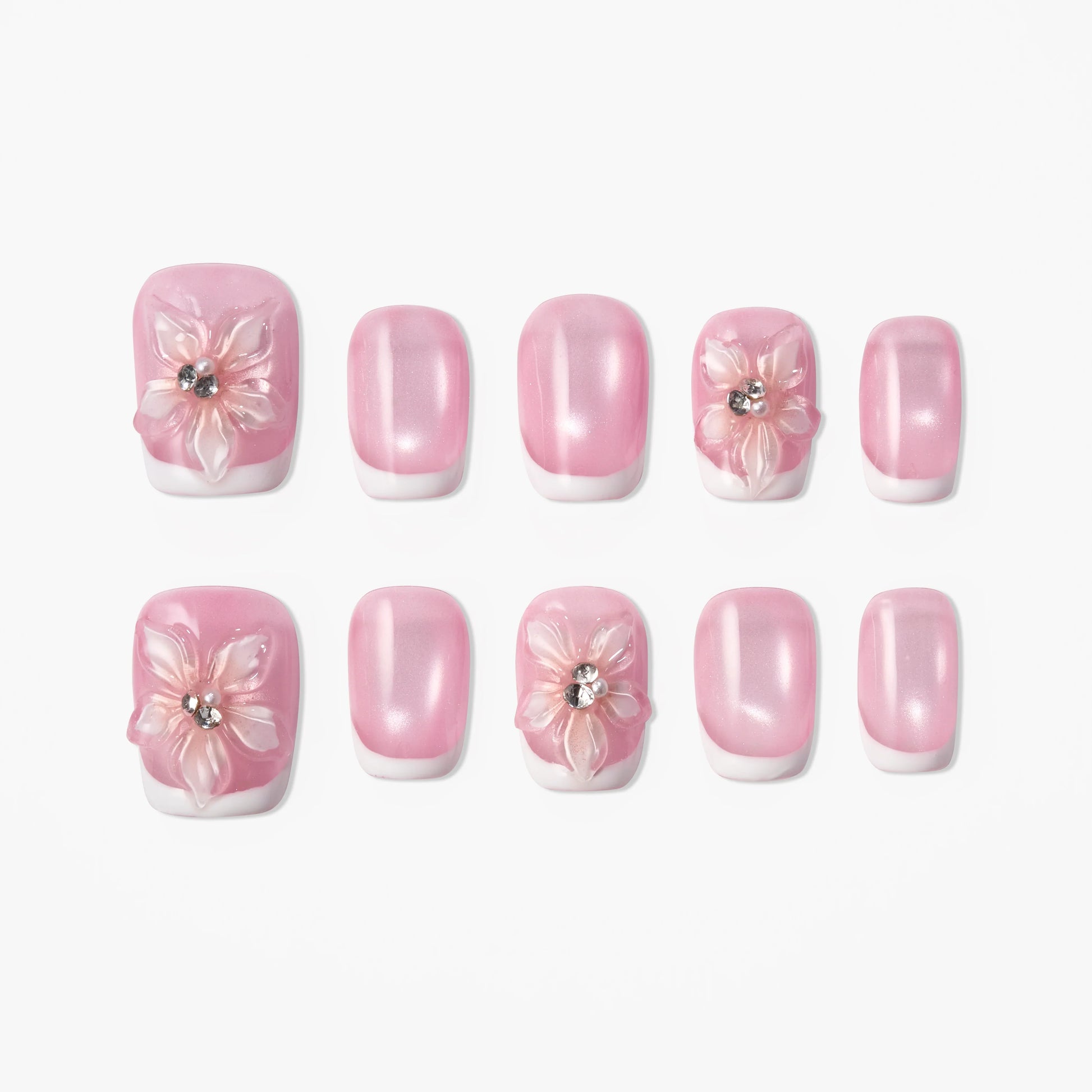 Pink French tip press-on nails with 3D floral designs and rhinestone accents