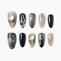 Handmade press-on nails with black, silver, and nude spider, web, and flame nail art designs.