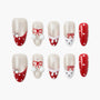 Handmade red and white festive press-on nails with snowflake, polka dot, and bow designs