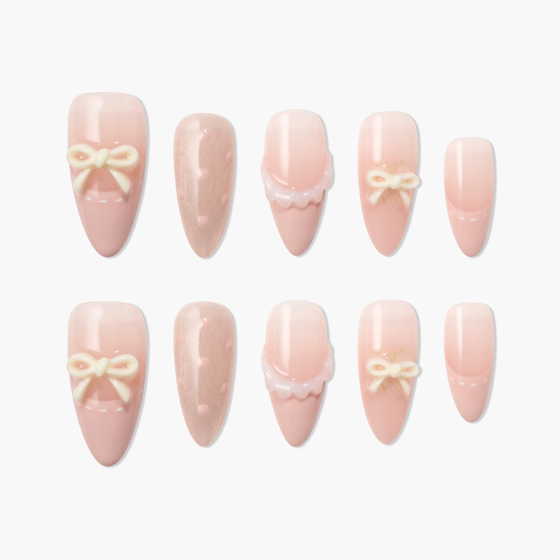Pink press-on nails with 3D bows, polka dots, and scalloped designs on white background