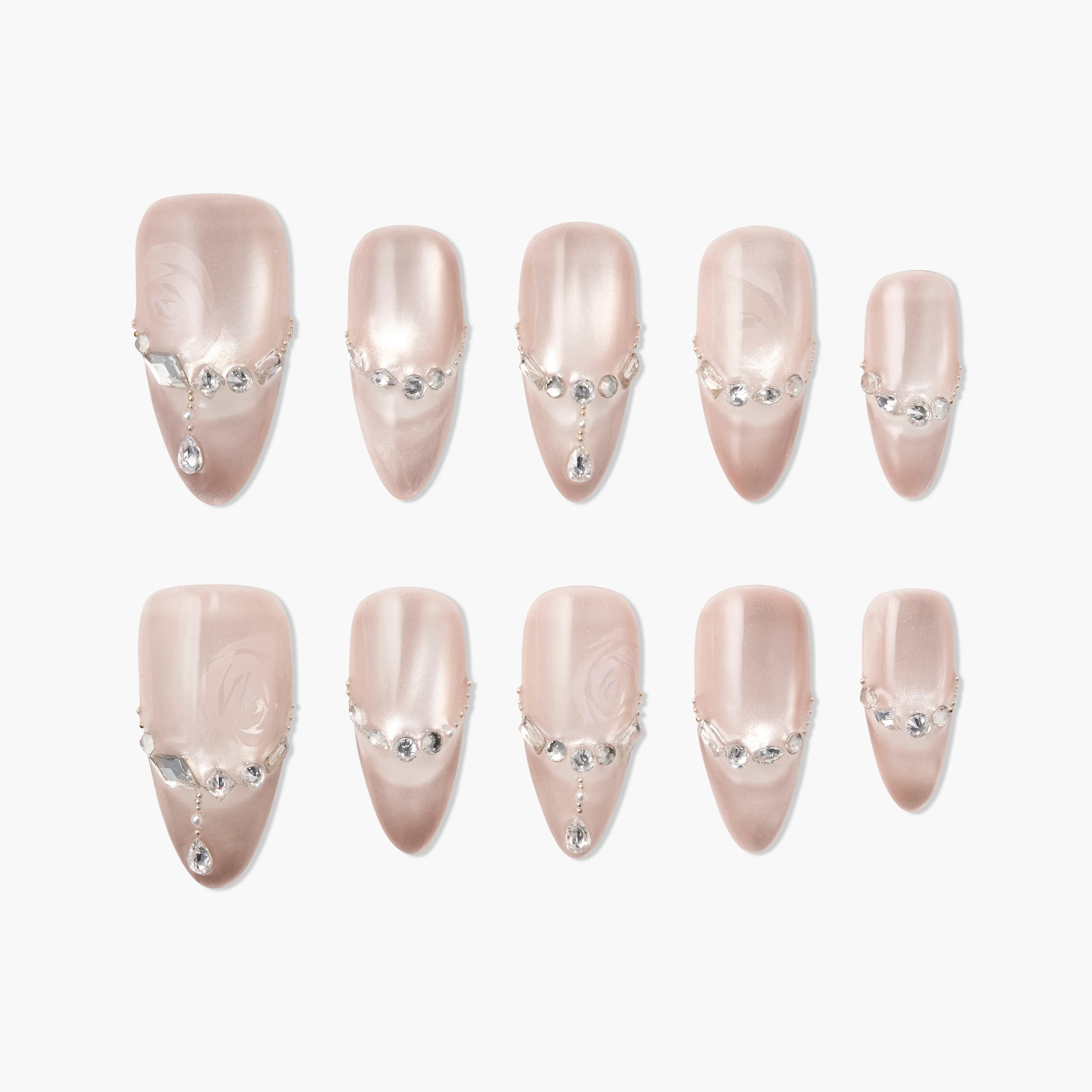 Glossy nude press-on nails with rhinestone and pearl accents, arranged on a white background.