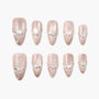 Glossy nude press-on nails with rhinestone and pearl accents, arranged on a white background.