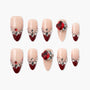 Handmade press-on nails with nude and deep red tips, adorned with rhinestones and gems.