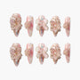 Handmade pink press-on nails with 3D flower and butterfly designs, gold accents, and pearl details