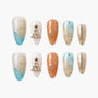 Handmade press-on nails with festive designs, rhinestone accents, ombré blue, gold, and orange tones