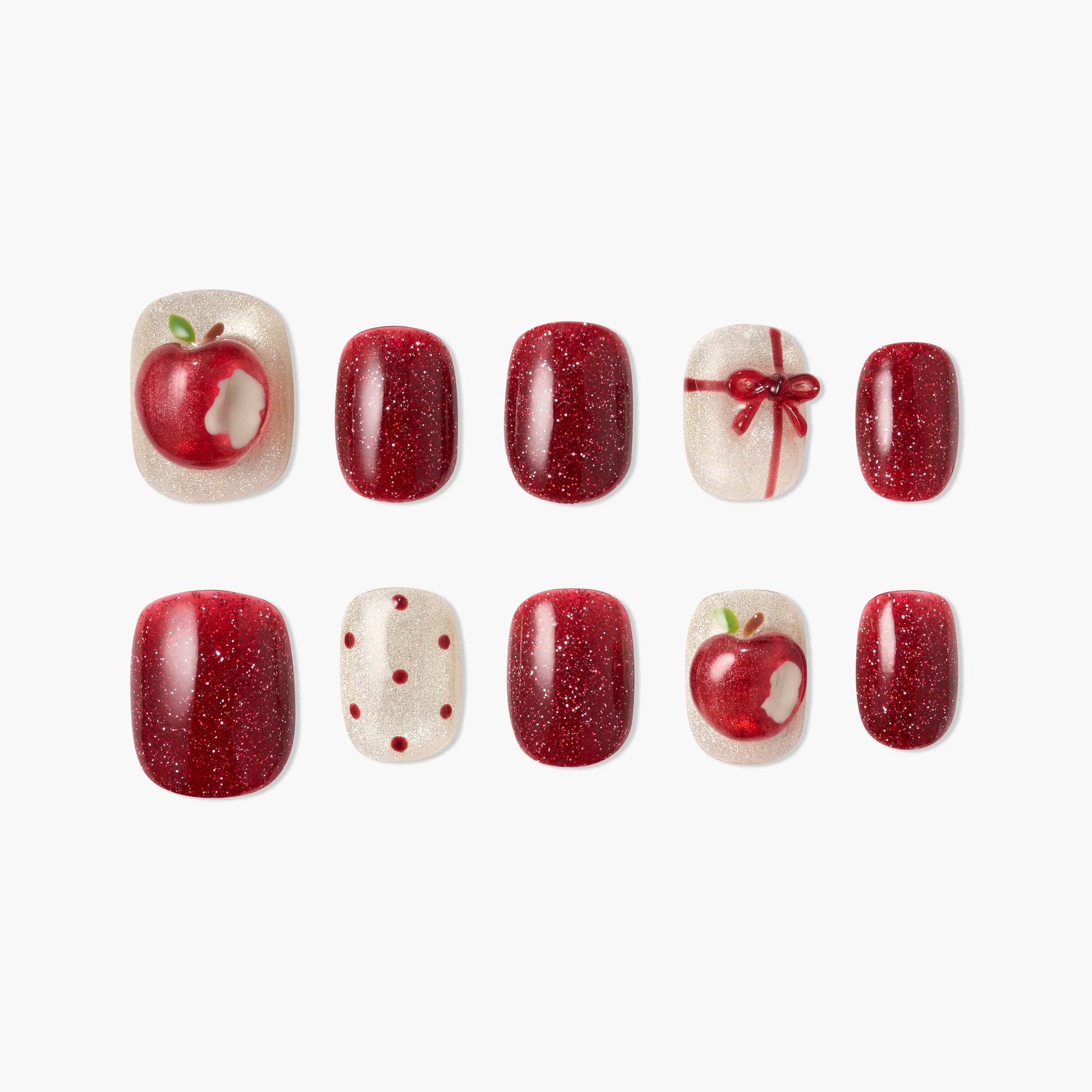 Red and glittery apple-themed press-on nails set with bow and polka dot designs on white background