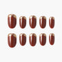 Set of press-on nails in glossy burgundy with metallic gold French tips on white background.