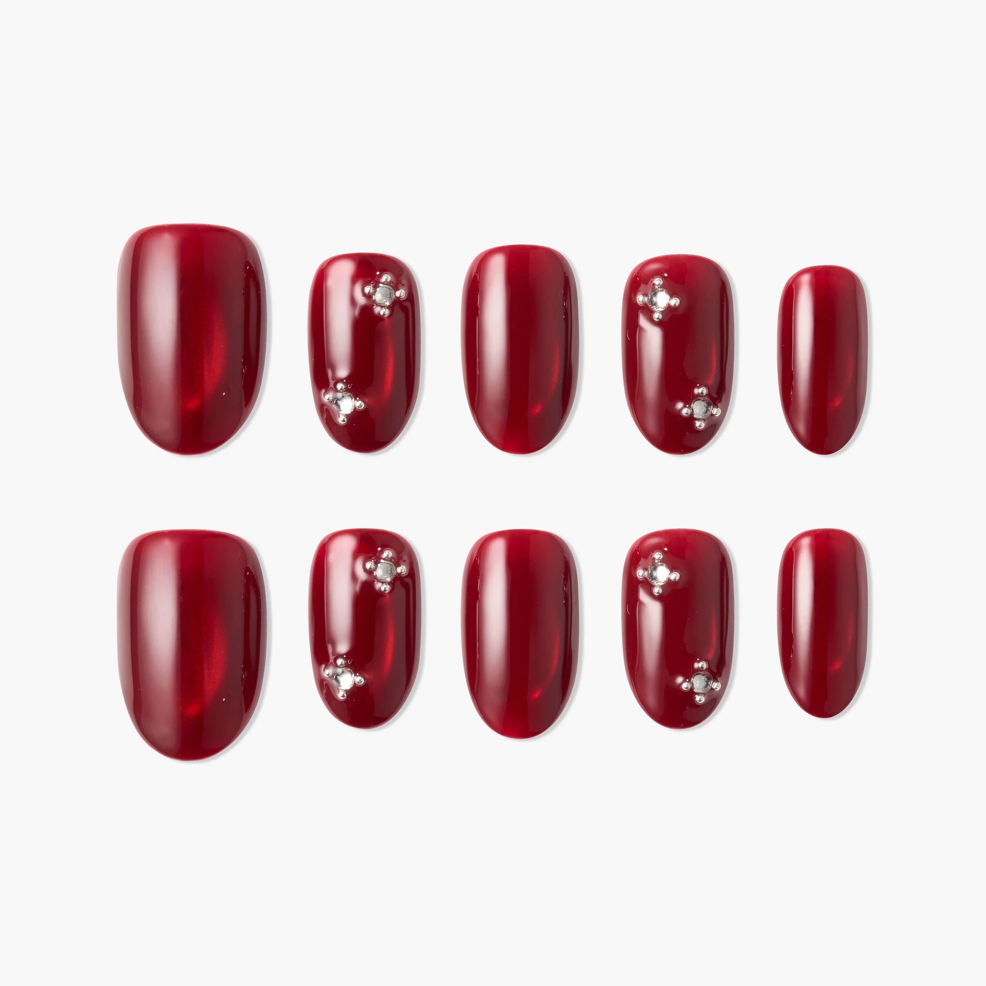 Set of glossy red press-on nails with rhinestone accents, arranged on a white background.