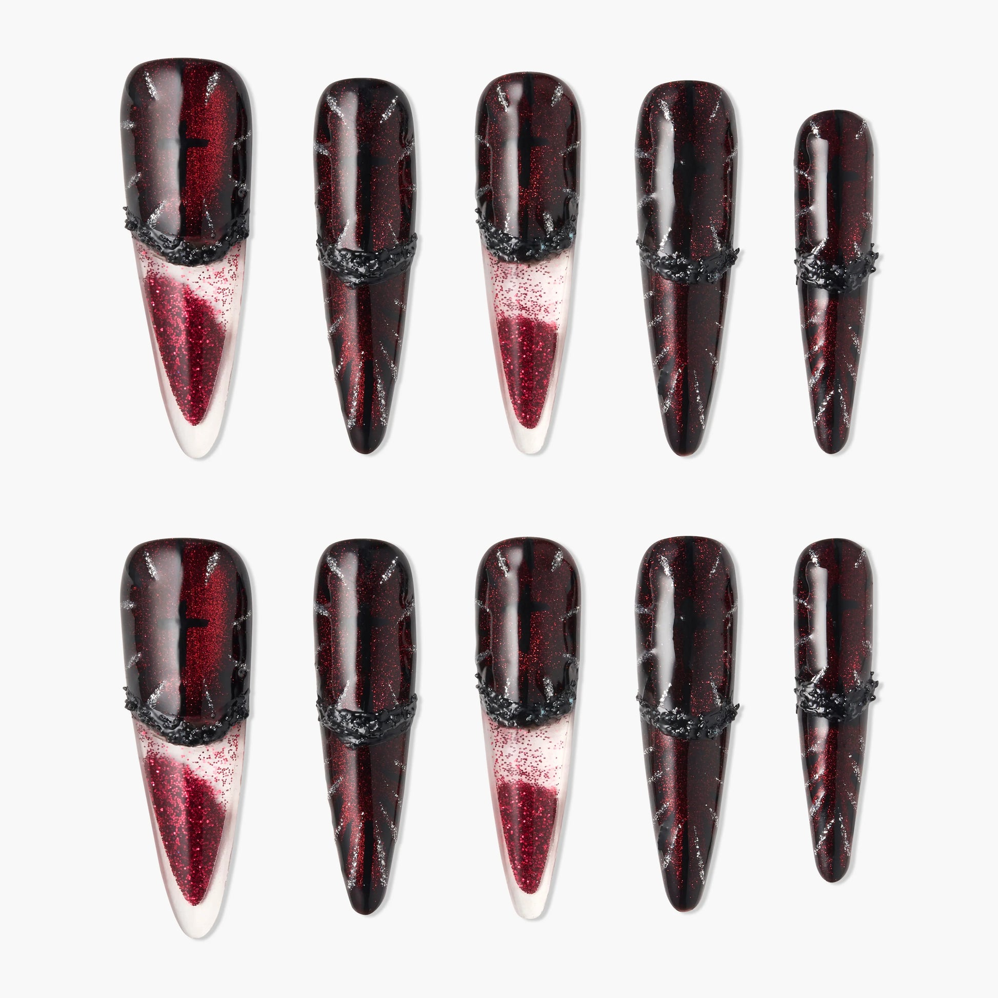 Glossy red and black stiletto press-on nails with glitter and textured black accents, arranged on white background.