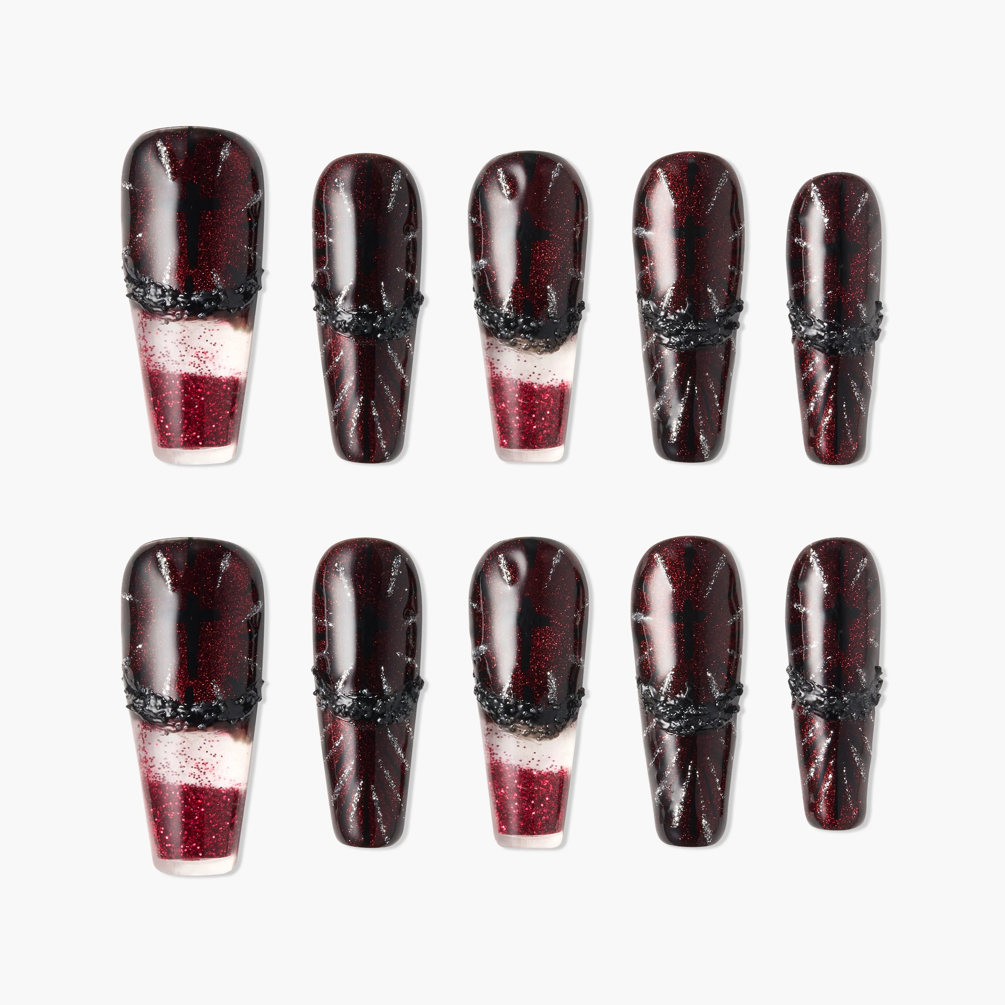 Glossy red and black press-on nails with glitter and black textured accents, arranged in two rows.