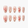 Handmade pink press-on nails with goldfish, glitter, and 3D floral designs arranged on white background