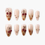 Handmade press-on nails with nude and gold marble design, cherry art, and gem accents.