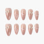 Set of handmade nude pink press-on nails with glitter, pearl accents, and small 3D bows