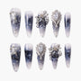Handmade press-on nails with black and white marble design, metallic bow and rhinestone accents
