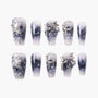 Handmade press-on nails with blue marble design, silver glitter, 3D bows, stars, and pearl accents