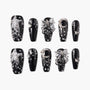 Black press-on nails with silver glitter stars, moons, bows, and 3D pearl accents