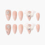 Nude pink press-on nails set with rhinestones, pearl accents, and 3D white bows on a white background