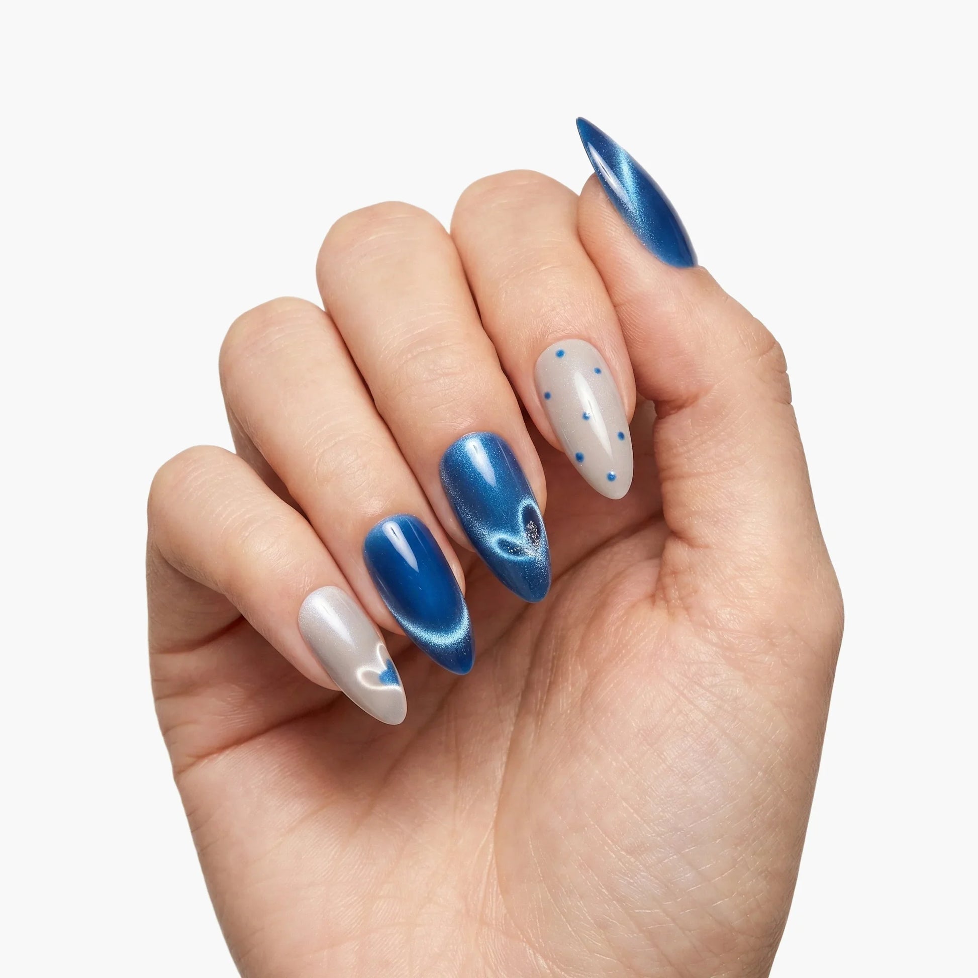 Hand with almond-shaped blue and silver press-on nails, featuring heart and polka dot designs.