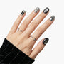 Hand with black and silver celestial-themed press-on nails and star and moon rings