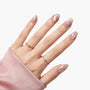 Hand with iridescent pink press-on nails featuring subtle wave patterns and star accents