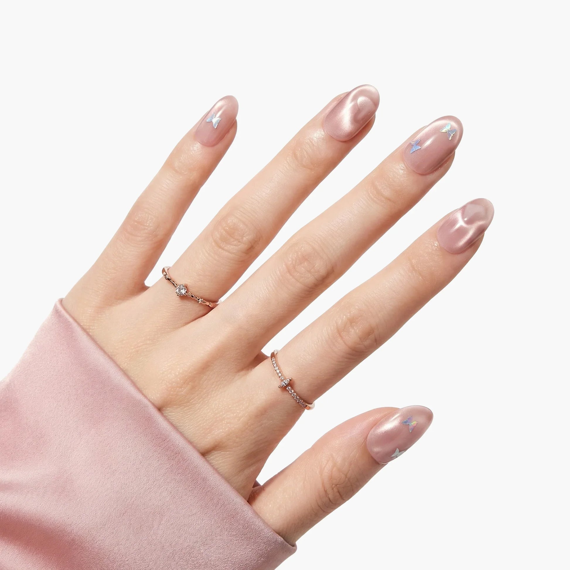 Hand with iridescent pink press-on nails featuring subtle wave patterns and star accents