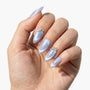 Hand with iridescent press-on nails in almond shape, featuring silver and pearl accents.