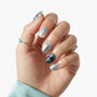 Hand with silver and teal press-on nails featuring star and gem accents, metallic finish