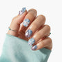 Hand with glossy lavender and blue press-on nails, 3D floral accents and pearl details