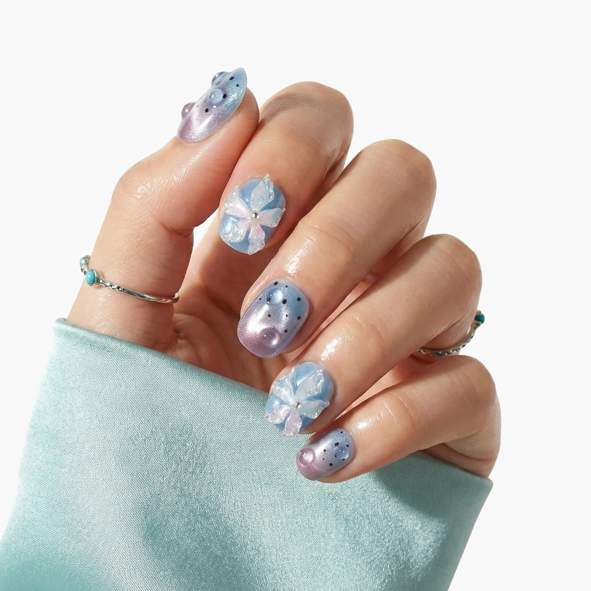 Hand with glossy lavender and blue press-on nails, 3D floral accents and pearl details